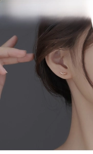 Detailed model view of elegant silver ear studs featuring a curved row of sparkling crystals
