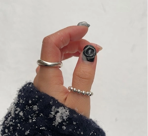 Detail of minimalist 925 sterling silver beaded and wide band rings on a hand