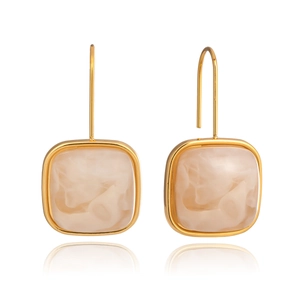 Détail de boucles d'oreilles carrées en résine avec monture dorée et texture marbrée beige