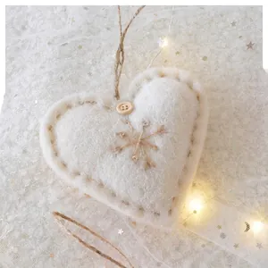 Close-up of heart-shaped wool felt ornament with wooden button and embroidery detail