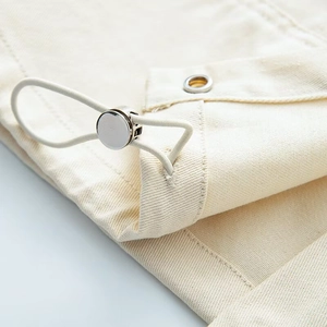Detailed close-up of beige twill fabric with a metallic drawstring toggle and elastic cord