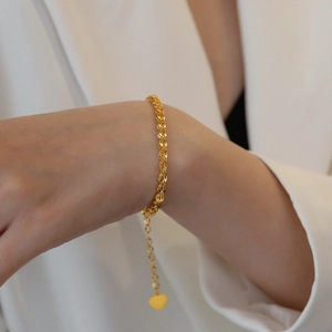 Chic gold-plated stainless steel woven bracelet with heart pendant on female wrist