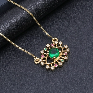 Detailed close-up of a golden evil eye pendant with green zircon and multicolor crystals