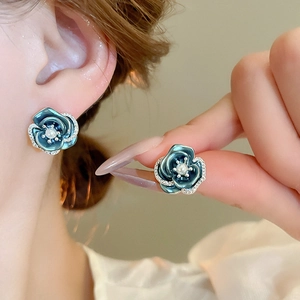 Macro detail of blue camellia flower earrings with pearl center and sparkling crystals