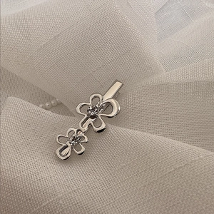 Détail d'une pince à cheveux fleurie en argent avec pétales ajourés et strass brillants