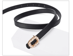 Detail of slim black leather belt featuring an oval buckle with pearls and rhinestones