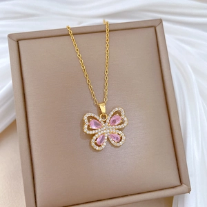 Elegant gold butterfly pendant necklace with pink gemstones and crystals on jewelry box