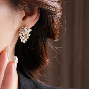 Close-up of golden floral stud earrings with marquise-cut cubic zirconia worn by a model