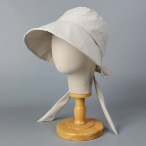 Detail view of beige wide-brim sun hat with back split ribbon design on a wooden stand