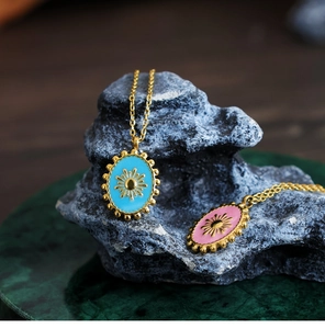 Macro detail of oval sunburst pendants in sky blue and pink enamel with 18K gold plating