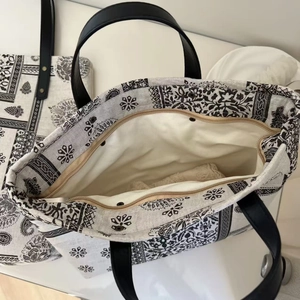Detail of paisley print tote bag with secure zipper closure and reinforced leather handles