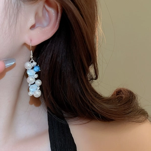 Detailed view of elegant freshwater pearl and blue gemstone drop earrings on a model