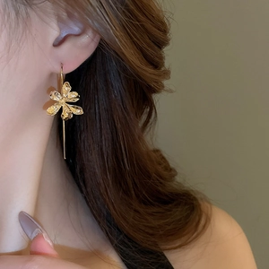 Detailed view of elegant gold iris flower drop earrings on model with retro French style