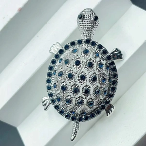 Detailed view of silver turtle brooch with dark blue rhinestones for women coat dress accessory