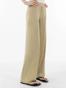 Detail view of khaki wide-leg pants showing draped fabric and drawstring waist design