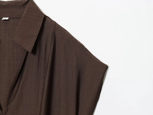 Gros plan du col de chemise marron foncé à rayures verticales avec détail de ceinture