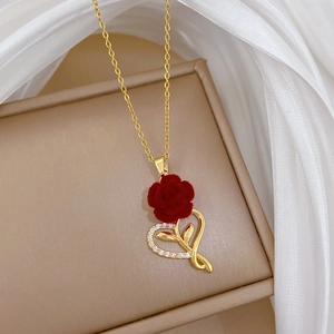 Close-up of golden necklace featuring a red flocked rose and diamond-encrusted heart charm
