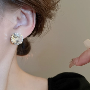 Close-up of a gold-toned crystal stud earring on model showcasing geometric luxury design