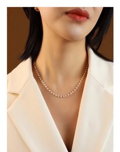 Elegant woman in white blazer wearing a multi-layered pearl choker necklace