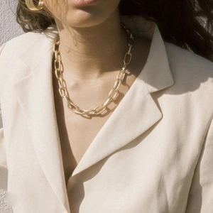 Polished 18k gold plated chunky chain necklace worn by model in beige suit blazer