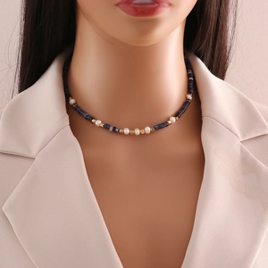 Detail of beaded necklace with blue natural stones and white pearls worn by a model