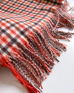 Detailed close-up of the red and black plaid pattern and fringe on the warm winter scarf