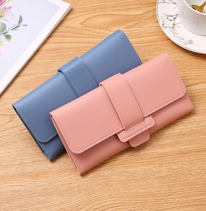 Flat lay of pink and blue pebble grain PU leather tri-fold wallets on a wooden table