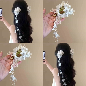 Detail of white floral lace hair clip with pearl tassels and golden metal duckbill clamp