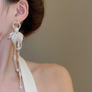 Detail of floral earrings with pearl tassels and crystal studs on a model