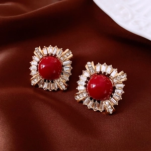 Detail of vintage round earrings with red center stone and crystals on silk background