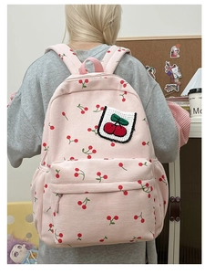 Dettaglio dello zaino in velluto a coste rosa con motivi a ciliegia e toppa a ciliegia intrecciata