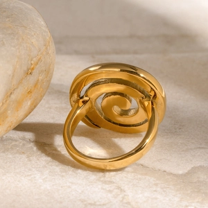 Polished gold spiral stainless steel ring on elegant marble stone pedestal background