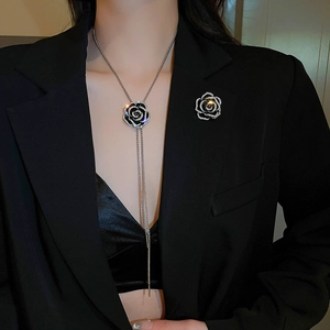 Détail du collier et de la broche fleur de camélia avec strass sur un blazer noir