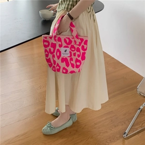 Detailed view of pink leopard print tote bag styled with a minimalist beige dress