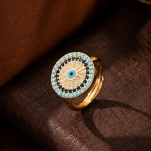 Golden Evil Eye open ring with blue and white crystals on dark leather background