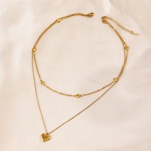 Collier double rang doré avec pendentifs en forme de cœur sur un fond en soie élégante