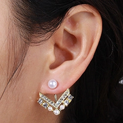 Detail view of gold star and moon ear jackets with white pearls and sparkling crystals
