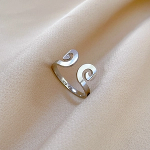 Macro view of silver adjustable ring with spiral cloud motifs on soft satin fabric