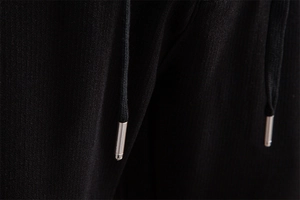 Detail of premium black textured fabric with metallic drawstring tips on casual trousers