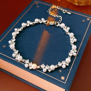 Macro detail of elegant pearl and zircon bracelet on navy book with lobster clasp
