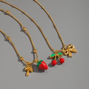 Detail of 18K gold necklaces featuring red strawberry, cherry, and mushroom pendants