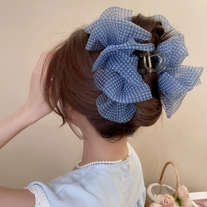 Détail d'une pince à cheveux en tissu à carreaux bleus sur une queue de cheval