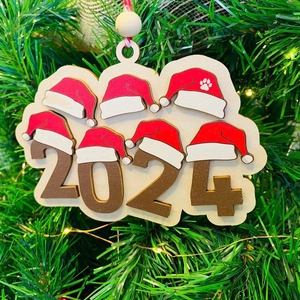 2024 wooden Christmas tree ornament with festive red hats on green pine background