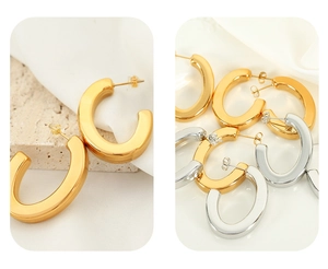 Close-up of polished C-shaped hoop earrings in gold and silver stainless steel