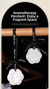 Detailed view of a white camellia plaster aroma diffuser with a black silk ribbon