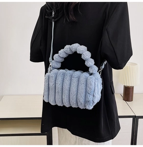 Blue fuzzy plush handbag with striped texture and round top handle detail on black outfit