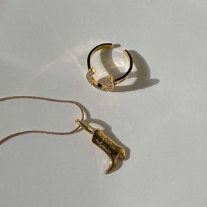 Detailed view of a gold horseshoe ring with crystals and a cowboy boot pendant necklace