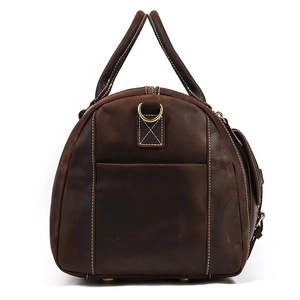 Close-up of vintage leather travel bag with white stitching and bronze hardware detail