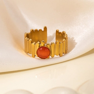 Detail of gold titanium steel ring with orange cat eye stone and gear-shaped band texture