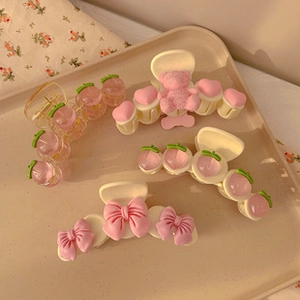 Flat lay of pink and cream hair clips with butterfly and peach designs on a tray